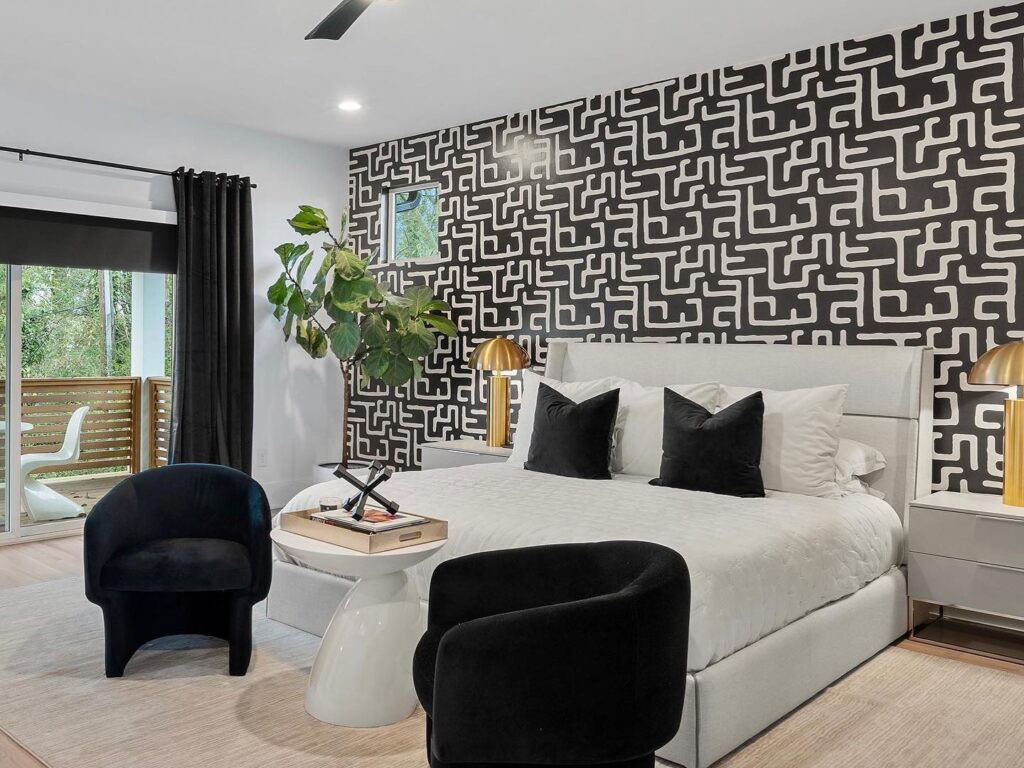 Modern bedroom with geometric wallpaper and decor.