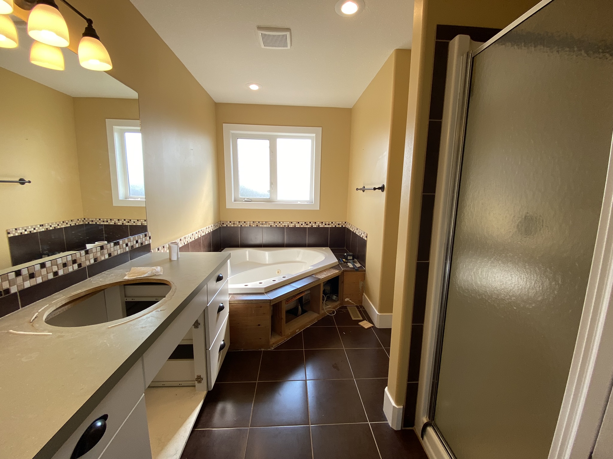 Original bathroom before renovation. Dated corner tub and small shower
