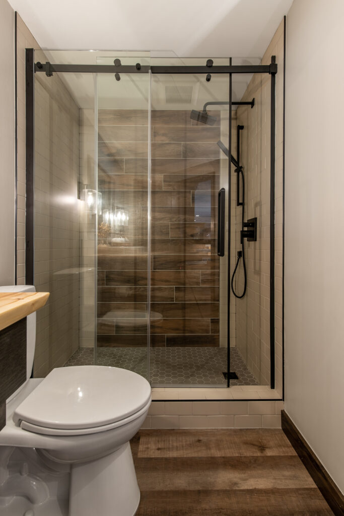 Modern bathroom with glass shower and wood accents. Residential Bathroom Interior Design. In-Awe Interiors Lethbridge